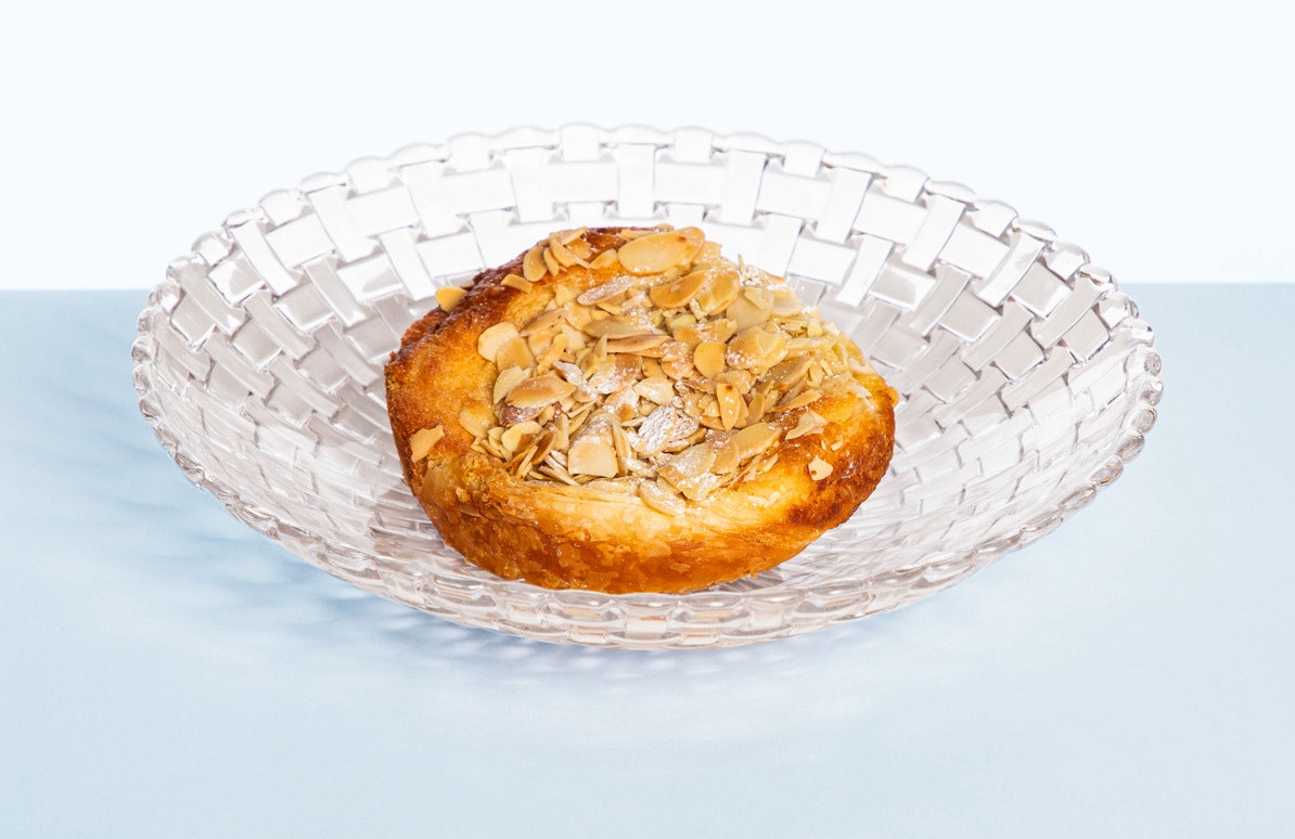 A almond croissant on a glass plate.